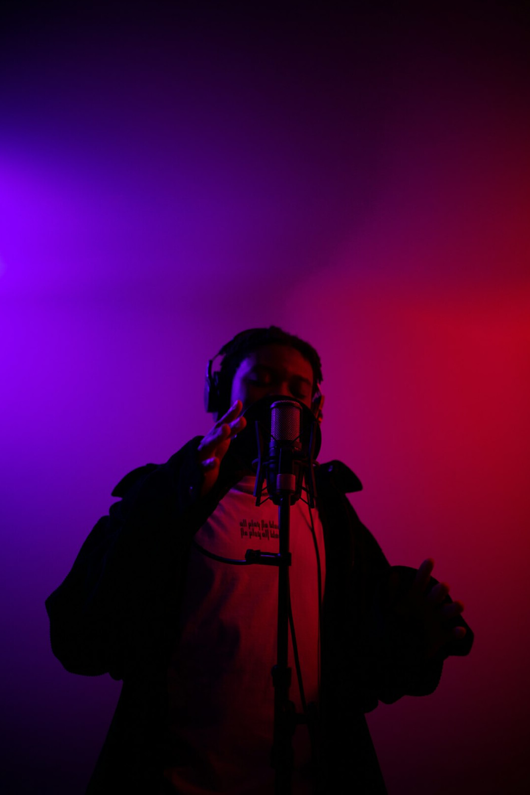 Laechelnde Podcast- und Videoproduzentin mit Kopfhoerern vor einem Mikrofon