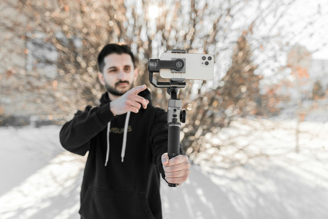 Junger Creator filmt ein vertikales Video mit dem Smartphone auf einem Gimbal